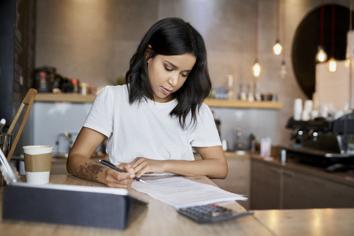 Young woman behind the counter of a cafe reviewing 2024 Last-Minute Medical Plan Tax Strategies