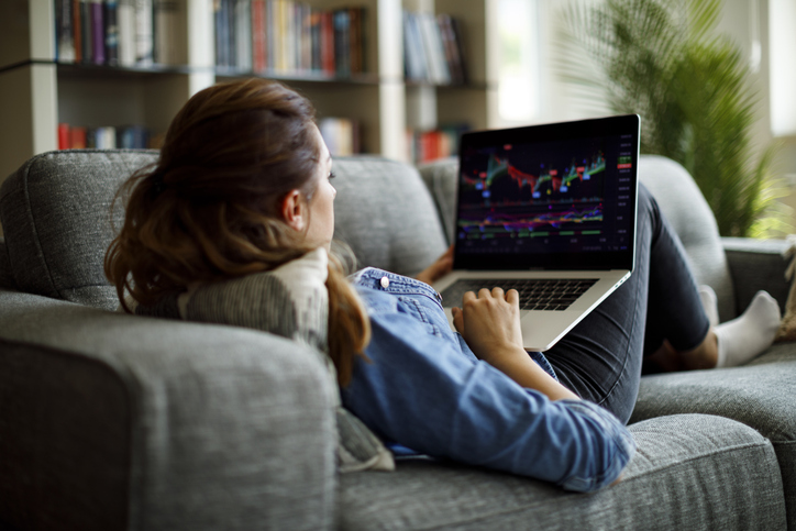 Woman lying on a couch with a laptop on her lap reviewing her 2024 stock tax strategies.